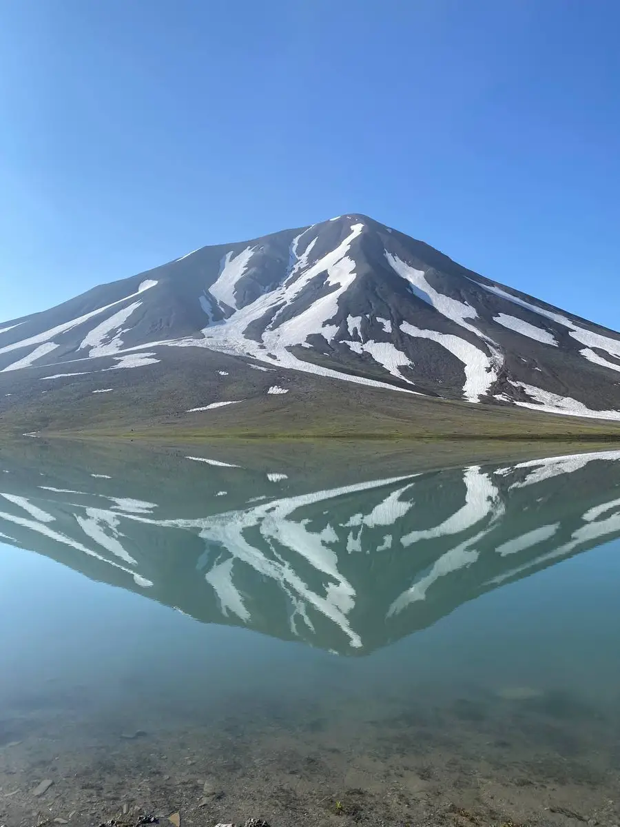 Вершина со снежниками отражается в зеркальной воде Келицади